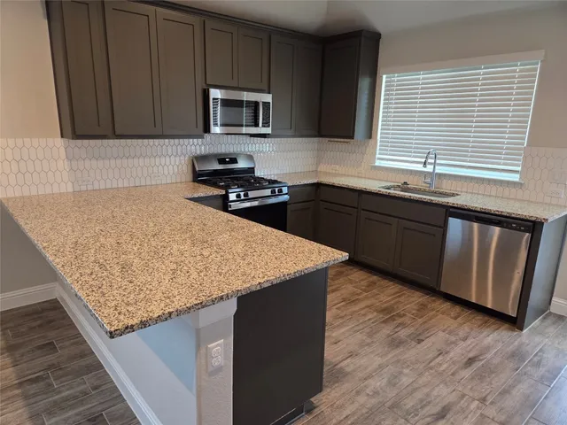 a kitchen with granite countertop wooden cabinets appliances and a window