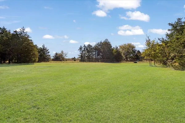 a view of a green field and trees