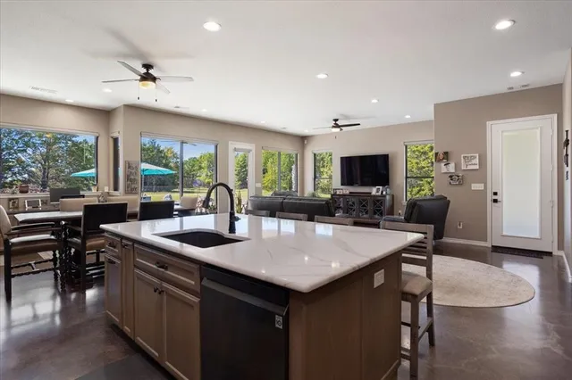 a open kitchen with stainless steel appliances granite countertop a sink a stove and a refrigerator with wooden floor