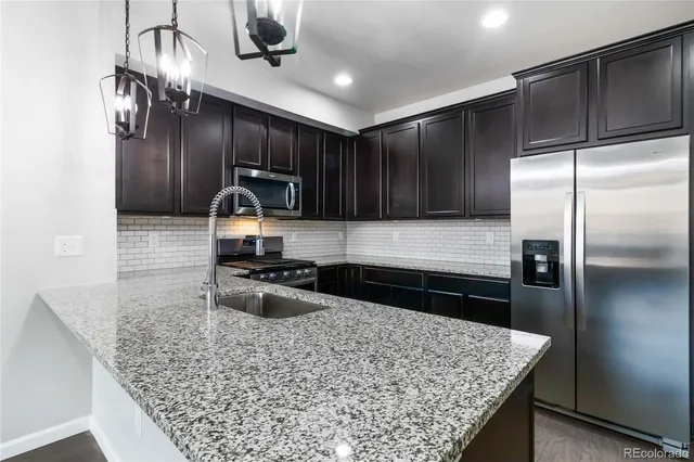 a kitchen with stainless steel appliances granite countertop a sink stove and refrigerator