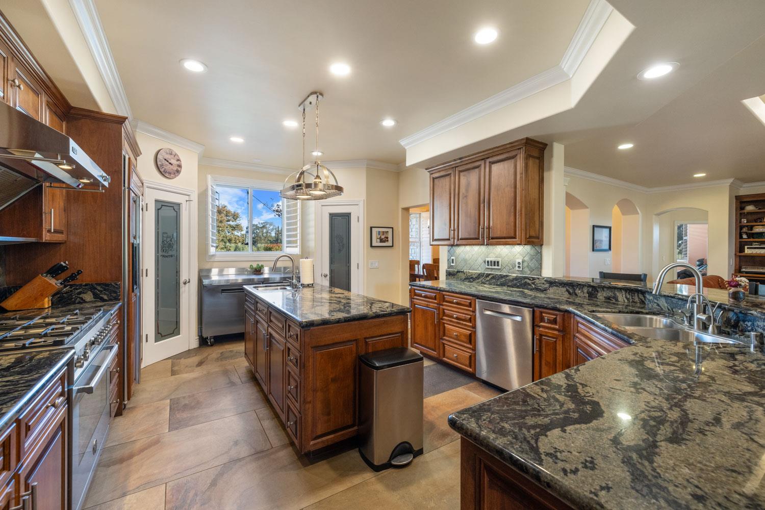 5288 West Kile Road Lodi, CA 95242 - Photo 23 of 45 a kitchen with stainless steel appliances granite countertop a stove top oven a sink dishwasher a dining table and chairs