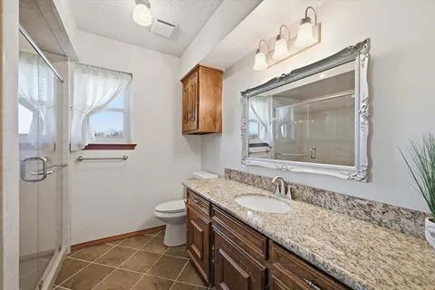 a bathroom with a granite countertop sink a toilet and a mirror