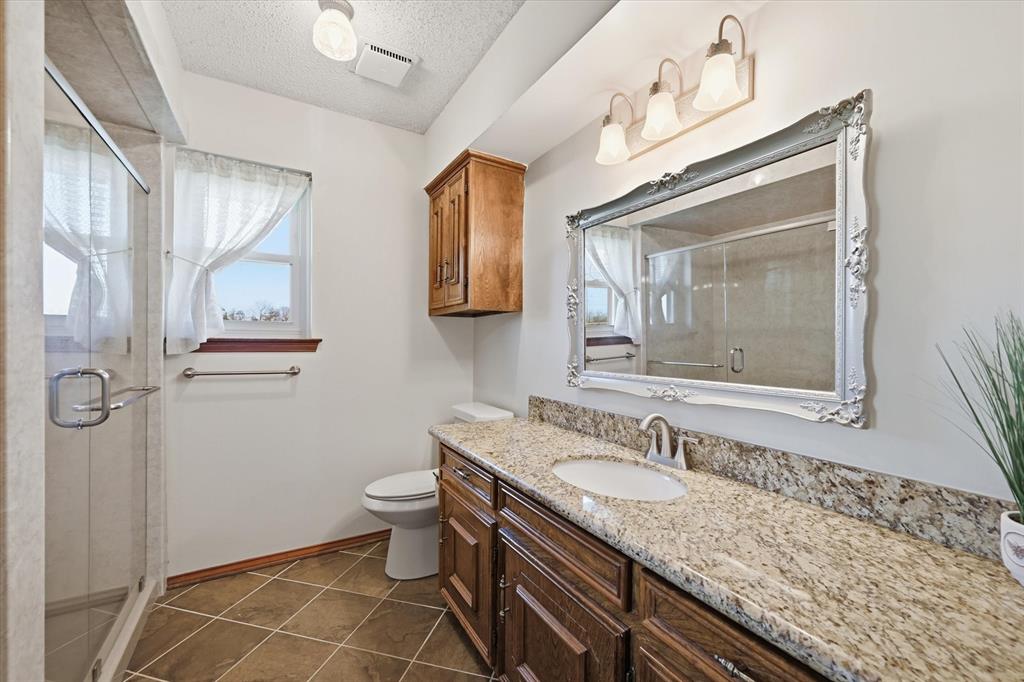 12099 County Road 1028 Blue Ridge, TX 75424 - Photo 24 of 36 a bathroom with a granite countertop sink a toilet and a mirror