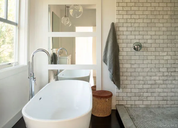 a white bath tub sitting next to a white sink and a mirror