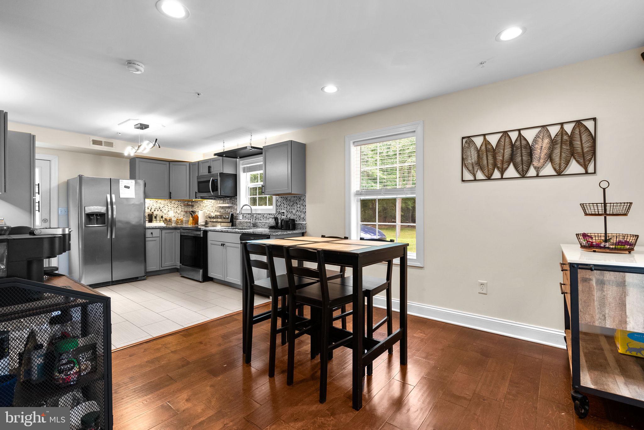 9621 Temple Hill Road Clinton, MD 20735 - Photo 18 of 48 a kitchen with stainless steel appliances kitchen island granite countertop a refrigerator a stove a sink a dining table and chairs with wooden floor