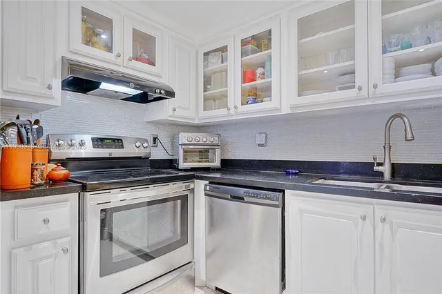 a kitchen with stainless steel appliances granite countertop a stove a sink and a microwave