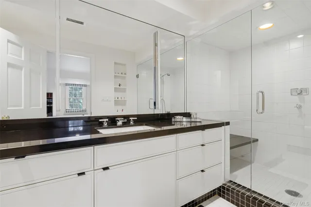 a bathroom with a granite countertop sink a toilet a large mirror and shower