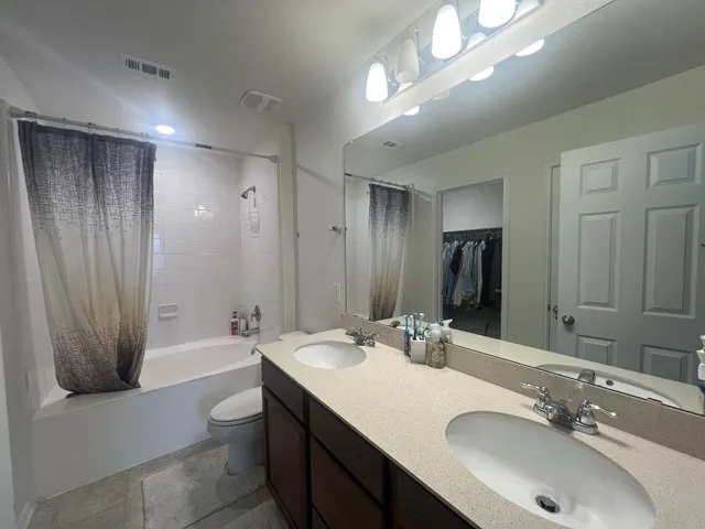 a bathroom with a double vanity sink a mirror and a bathtub