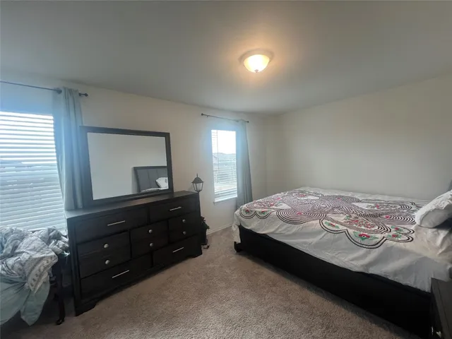 a bedroom with a bed and a dresser with mirror