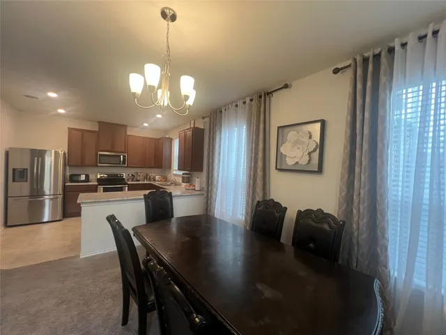 a dining room with wooden floor a chandelier a wooden table and chairs