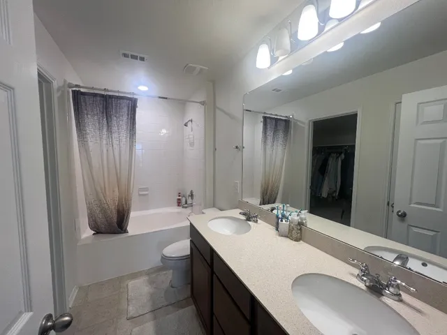 a bathroom with a double vanity sink a large mirror and a bathtub