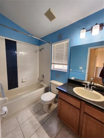 a bathroom with a granite countertop sink toilet mirror and bathtub