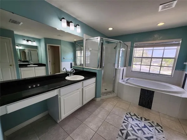 a large bathroom with a large tub sink and glass door