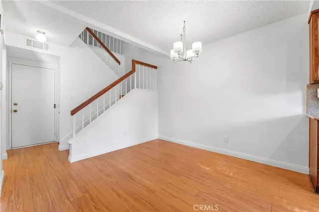 a view of an empty room with wooden floor and stairs
