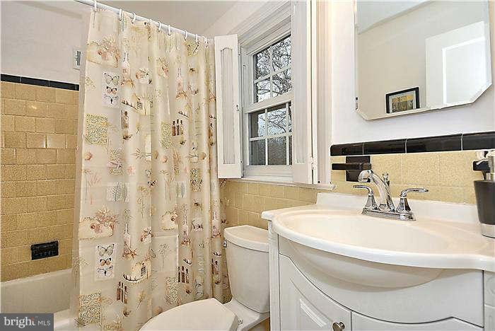 9602 Sutherland Road Silver Spring, MD 20901 - Photo 22 of 30 a bathroom with a sink a toilet and shower curtain