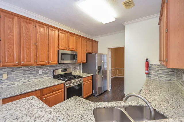 a kitchen with stainless steel appliances granite countertop a refrigerator sink and stove