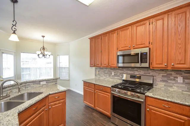 a kitchen with stainless steel appliances granite countertop a sink stove and microwave