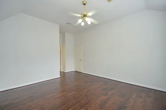 a view of an empty room with a chandelier fan