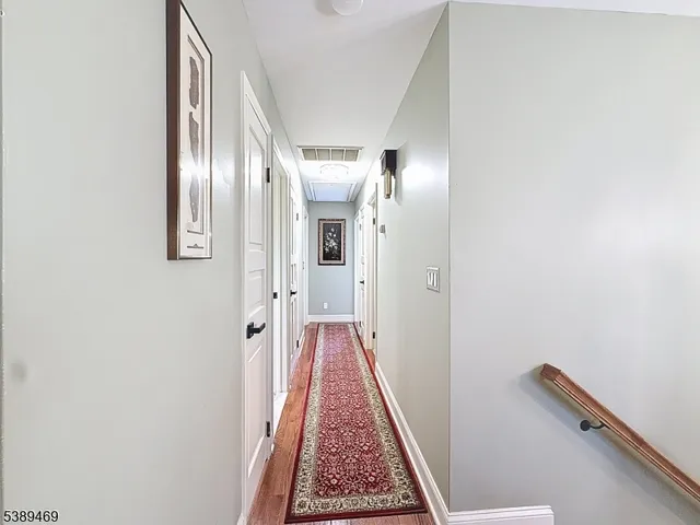 view of a hallway with wooden floor and a bathroom