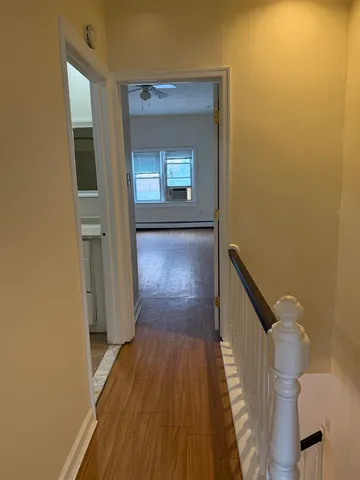 a view of a hallway with wooden floor and a bathroom