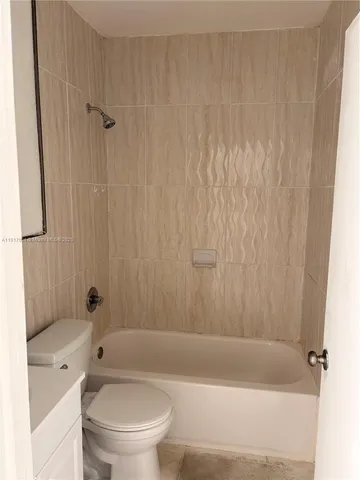 a bathroom with a bathtub shower sink vanity and toilet