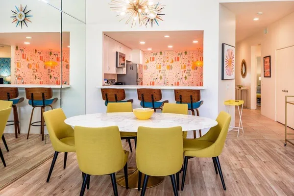 a view of a dining room with furniture one side kitchen view and wooden floor