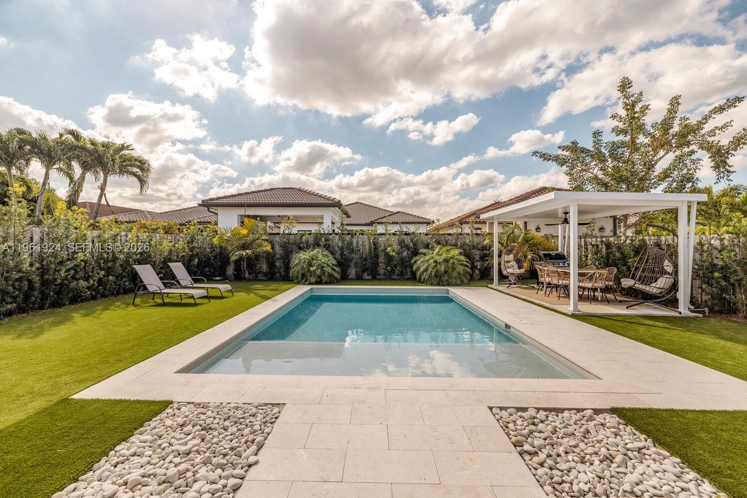 a view of swimming pool with lawn chairs and plants