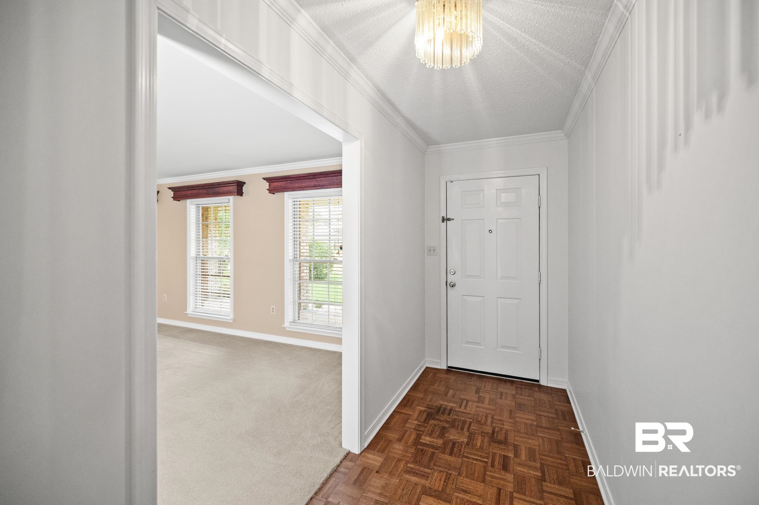303 West Palm Avenue Foley, AL 36535 - Photo 24 of 32 Interior space featuring a chandelier, a textured ceiling, crown molding, and dark parquet floors