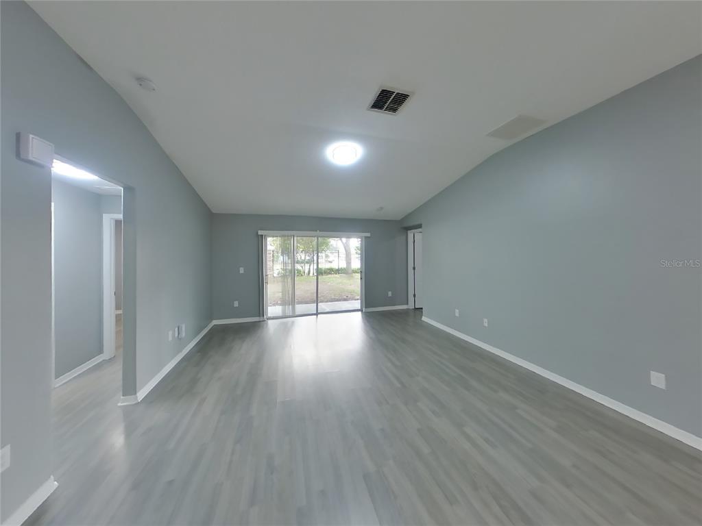 Undisclosed Address Spring Hill, FL 34609 - Photo 3 of 15 a view of an empty room with wooden floor and a window