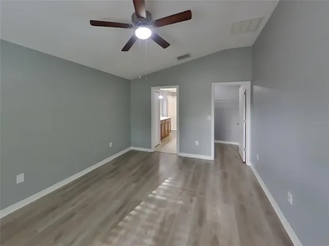 an empty room with closet and a ceiling fan