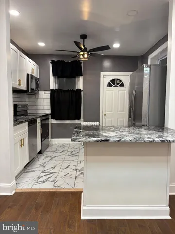 a view of a kitchen with kitchen island a sink stainless steel appliances and cabinets