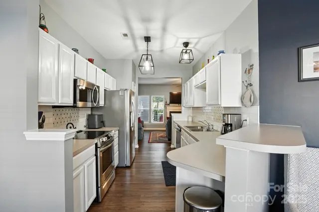 a kitchen with stainless steel appliances a sink a stove top oven a counter space and cabinets