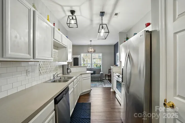 a kitchen with stainless steel appliances a sink dishwasher a refrigerator and cabinets with wooden floor