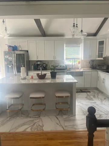 a kitchen with kitchen island granite countertop a table chairs sink and cabinets