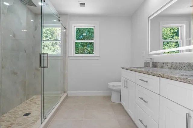 a bathroom with a granite countertop toilet a sink and a window