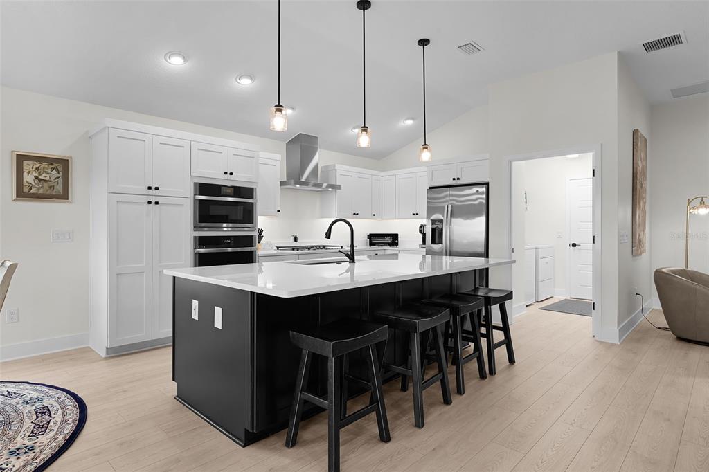 6776 Robinette Run, Unit ROBINETTE RUN The Villages, FL 34762 - Photo 6 of 52 a kitchen with kitchen island granite countertop a sink a center island a dining table and chairs