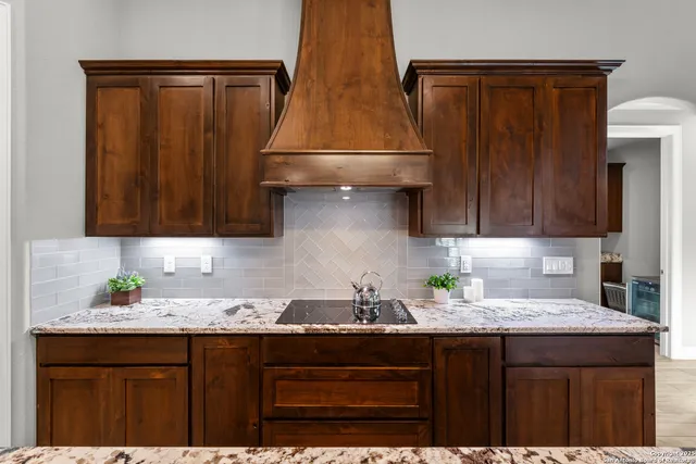 a kitchen with granite countertop a sink a stove and cabinets