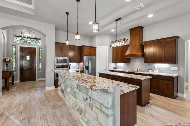 a large kitchen with granite countertop a large counter top space a sink appliances and cabinets