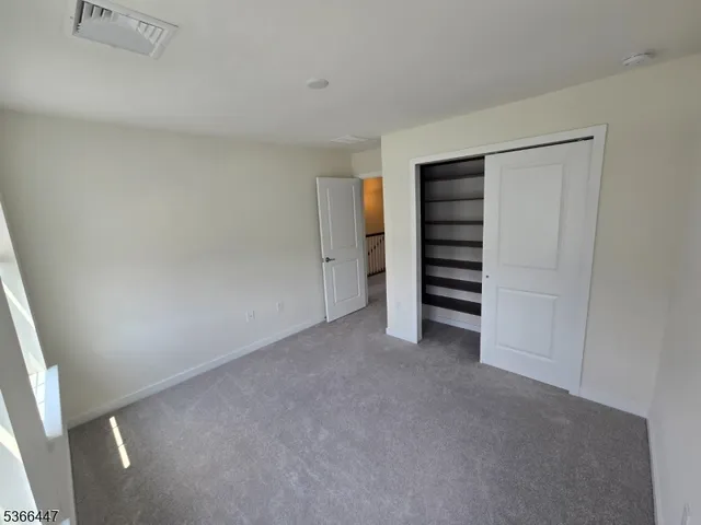 a view of an empty room with closet and racks