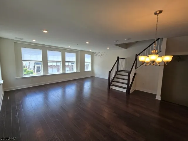 a view of an empty room with wooden floor and windows