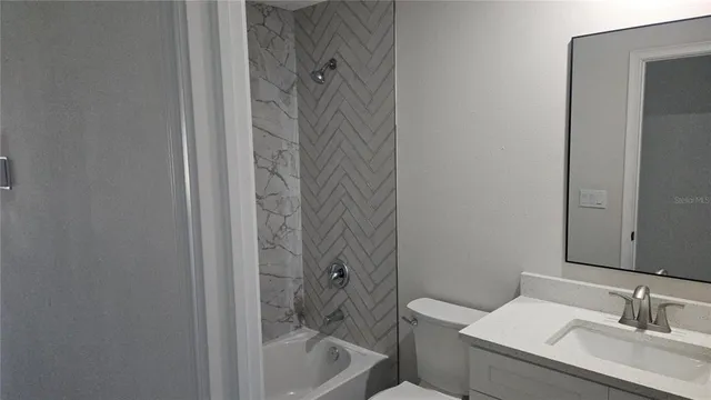 a bathroom with a granite countertop sink a toilet and shower