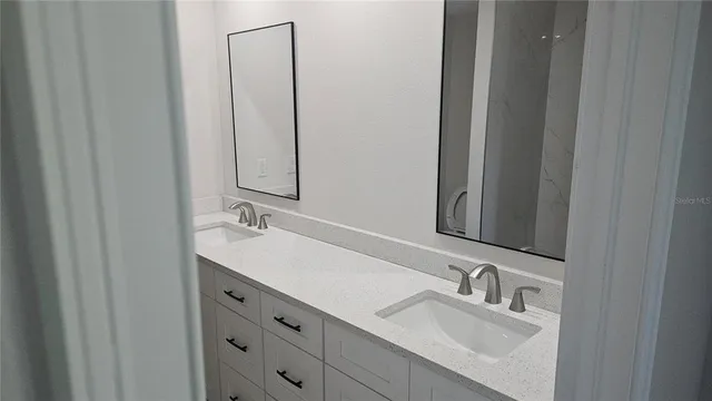 a bathroom with double sink and two mirror
