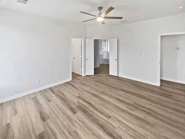 a view of empty room with wooden floor and ceiling fan