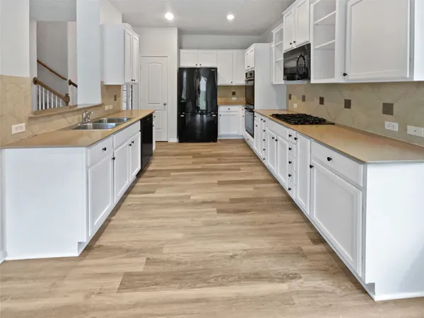 a large kitchen with stainless steel appliances kitchen island granite countertop a sink and cabinets