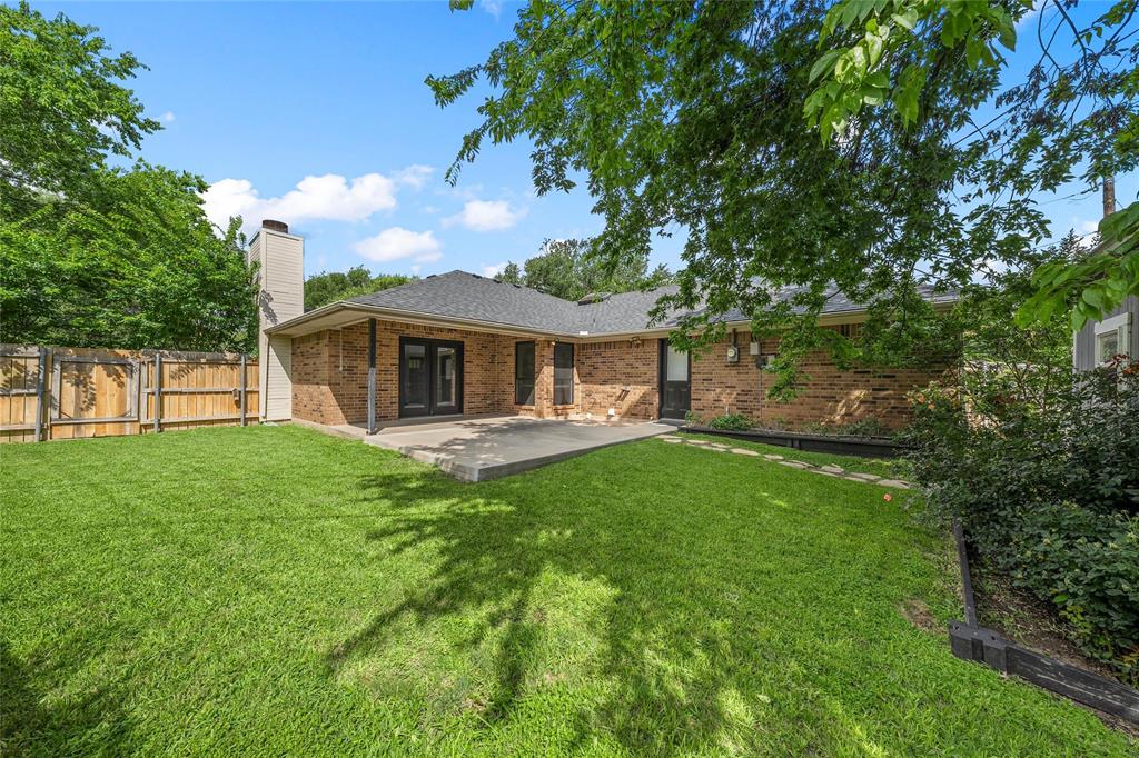 310 Ruth Drive Hewitt, TX 76643 - Photo 17 of 25 Spacious backyard featuring a concrete patio, a privacy fence, and a brick exterior with multiple windows and a double door