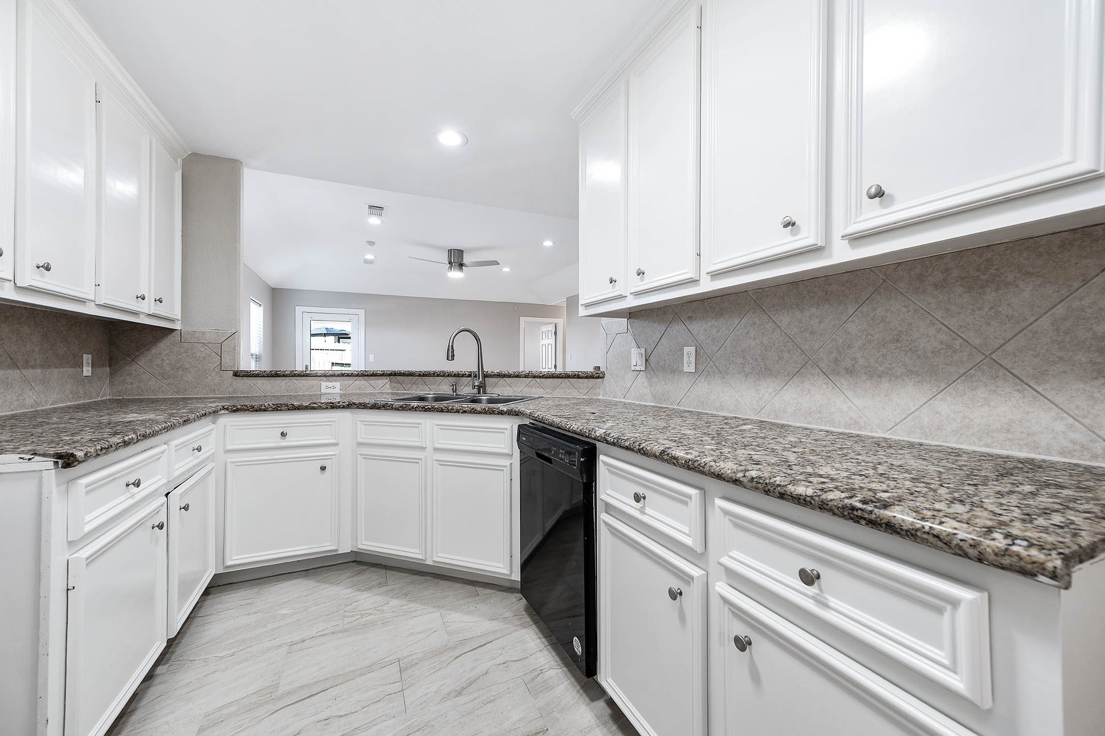 7308 Avenue R Galveston, TX 77551 - Photo 9 of 24 a kitchen with granite countertop white cabinets and white appliances