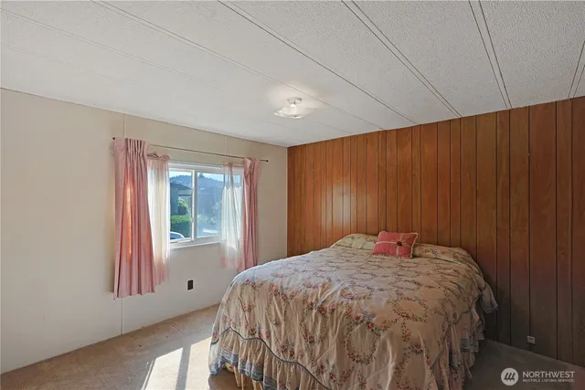a bed sitting in a spacious bedroom next to a window