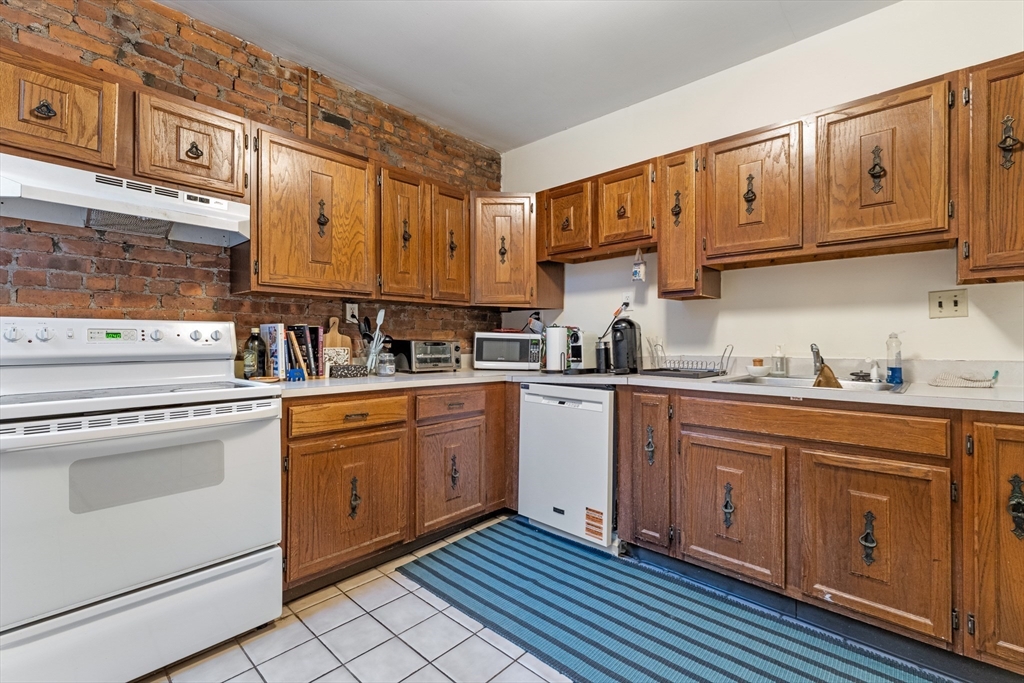 1408 Commonwealth Avenue, Unit 14 Boston, MA 02135 - Photo 7 of 12 a kitchen with stainless steel appliances granite countertop a sink and cabinets