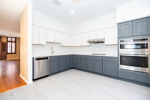 a kitchen with stainless steel appliances granite countertop a stove a sink and a refrigerator with wooden cabinets