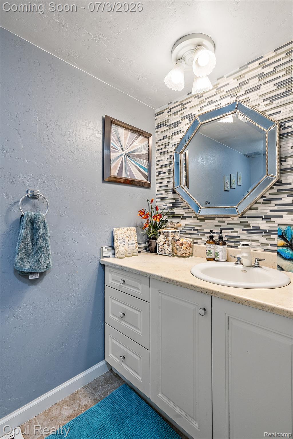 8855 Gross Road Dexter, MI 48130 - Photo 34 of 53 Bathroom vanity featuring light-toned cabinetry with drawer and cabinet storage, a light-colored countertop, and an integrated white sink